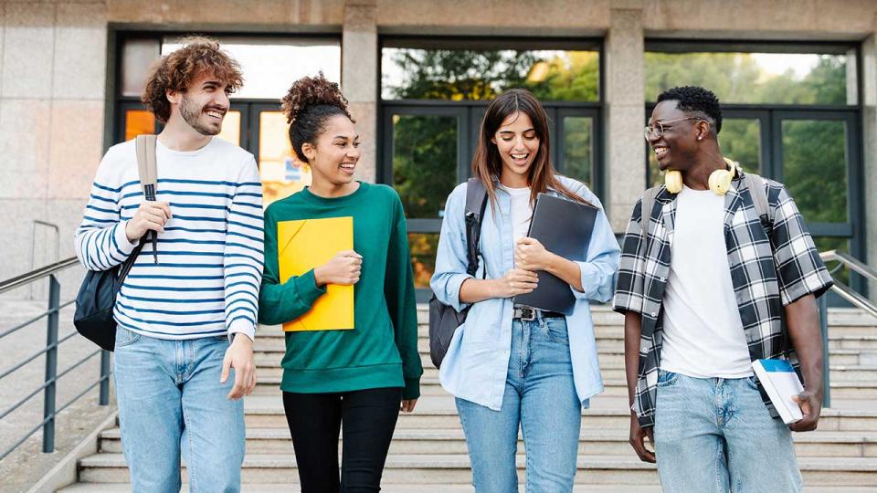 Schülergruppe läuft gemeinsam die Treppe vor einem Schulgebäude hinunter