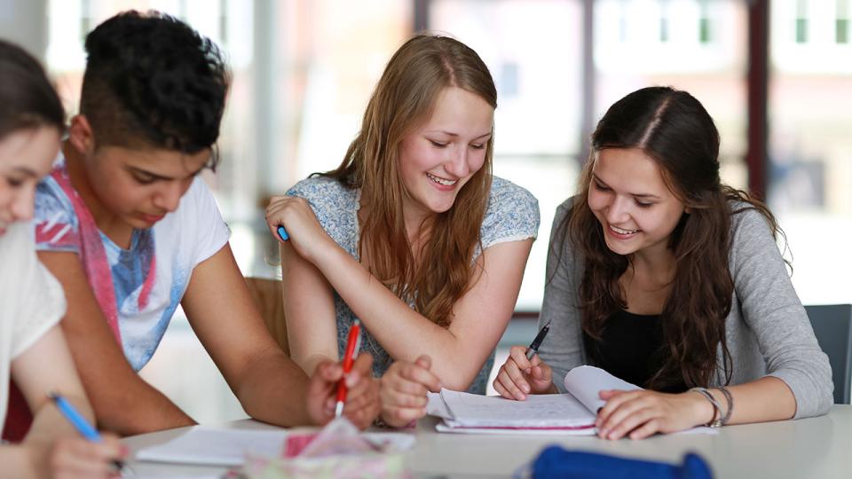 Eine Gruppe aus vier Schülerinnen und Schülern sitzt nebeneinander und lernt
