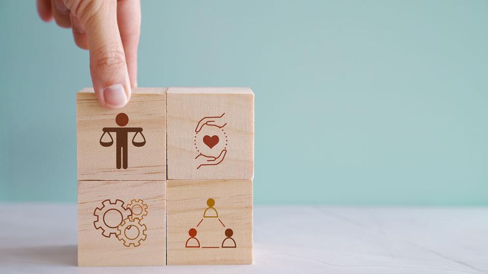 Hand hält Holzblock mit ethischen Symbolen, Geschäftsethik und Corporate Compliance Konzept